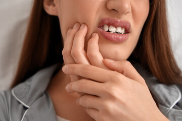 Young woman in pajamas suffering from toothache at home, closeup