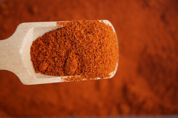 A Detailed CloseUp Image of Red Paprika Powder in a Wooden Spoon
