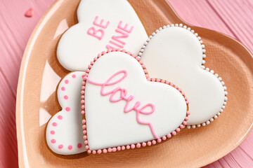 Plate with heart shaped cookies on pink wooden background. Valentine's day celebration