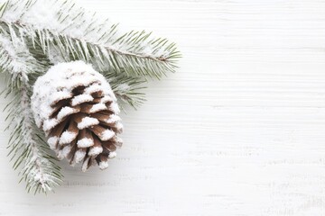Snow-dusted pine cone and branch on a white wooden background. Perfect for winter or holiday themed designs.
