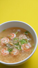 rice soup with shrimp in white bowl on yellow background