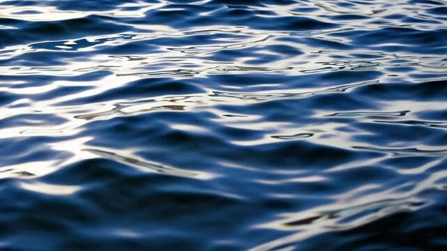 Rippling water surface with reflections, close-up view. Natural water texture and tranquility concept