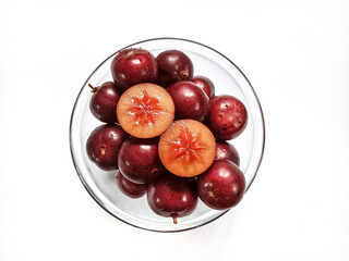 Flacourtia fruit in a bowl. Rukam, ramontchi, governor's plum, Indian plum, and Indian prune. Bowl of fruits on white background. 