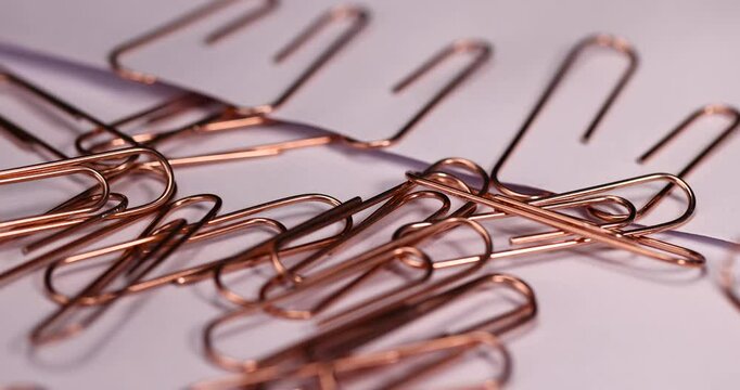 paper clips made of metal for the systematization of documents and paper, large-sized copper paper clips lie on white blank paper