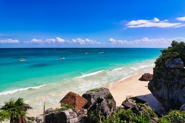 Fototapeta premium Beautiful sea views of the turquoise blue green waters of the Caribbean Sea with a viewing deck leading to the playa ruinas, or ruins beach at the late 13th century Mayan ruins of Tulum,Mexico