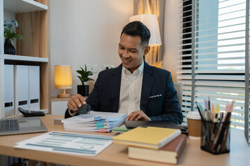 Image of handsome businessman is working in office, cheerful businessman entrepreneur professional working while sitting at office desk, accountant, marketing, employee is working alone in the office