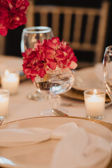 Elegant Table Setting with Crystal Vase, Red Flowers, and Candlelight for a Luxurious Wedding Reception