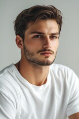 Fototapeta premium Portrait of a young man with clean-shaven face, looking off to the side. He has short brown hair and is wearing casual attire suitable for fashion or lifestyle branding.