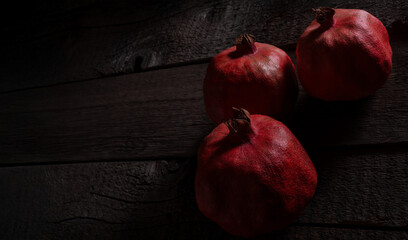 Pomegranate fruit on wooden old table surface. Selective lighting art photo.