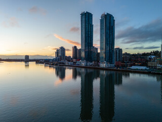 Obraz premium Modern Skyscrapers Reflecting in the Calm Waterfront at Sunset in New Westminster
