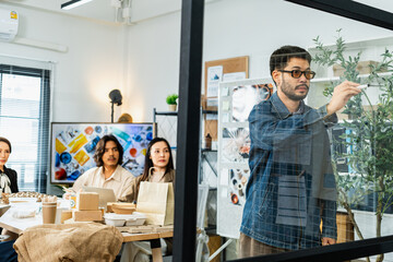 Creative team brainstorming and analyzing ideas on glass board during modern office meeting