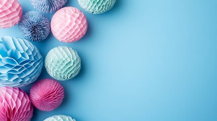 Pastel paper pom poms arranged on a blue background