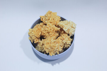 Rengginang or arangginang or rangginang in a small bowl on a white background. Traditional Indonesian snack made from sticky rice and then fried.