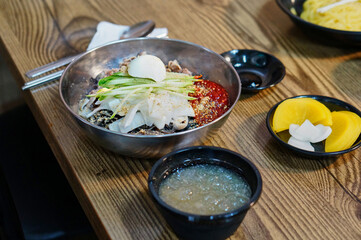 식탁 위에 차가운 비빔냉면이 놓여 있는 모습