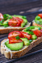 Avocado toast topped with tomato and green onion on a slice of carrot bread