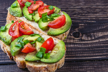 Avocado toast topped with tomato and green onion on a slice of carrot bread