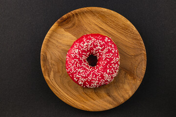 delicious donut that features vibrant red frosting and white sprinkles on top