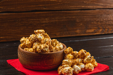 Snack, movie concept, caramelized popcorn in a wooden bowl on a red napkin