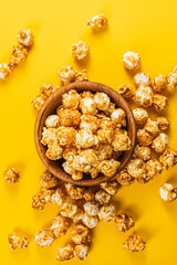 Snack concept Sweet caramelized popcorn in a wooden bowl on a yellow background