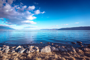 Serene Erhai Lake in Dali, Yunnan, China.  A picturesque view of calm waters, rocky shoreline, and...