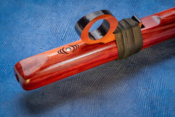 detail of native American style flute with fetish handcrafted from aromatic cedar wood against art paper
