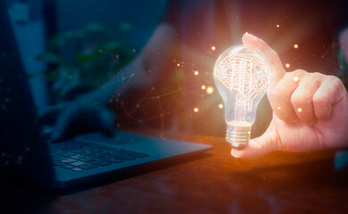 Businessman using laptop and holding glowing light bulb with artificial intelligence brain icon and...