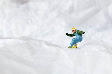 Miniature people  snowboarder dressed in vibrant winter gear, carving through a snowy slope