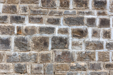 Rugged stone wall texture with rectangular grey and brown bricks