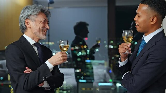 パーティー、祝杯、乾杯、ワイン、シャンパン、夜景、オフィス、グローバル、談笑、コミュニケーション、ビジネス、ビジネスパーソン、ビジネスマン、英会話、グラス、立食、会談、チームワーク、友人、イベント、式典、笑顔、スーツ、シニア、ミドルエイジ、中高年、日本人、男性、外国人、黒人、国際、グループ、社長、経営者、上司、部下、経営、マネジメント、企業、アルコール、お酒、飲酒、外交、祝福、宴会、祝宴、接待、ロ