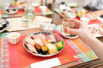 テーブルに並べられた沢山の料理とお酒を持つ女性の手