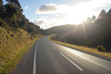 Naklejka premium Scenic highway winding through lush green hills, sun shining.
