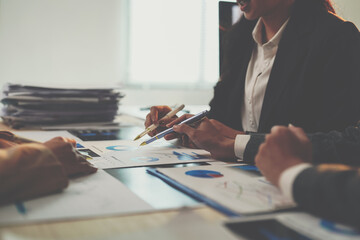 Business team members are pointing at charts and graphs, discussing financial data and analyzing company performance in a collaborative office environment