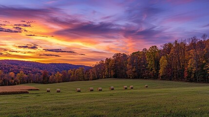 Fototapeta premium Serene Autumn Sunset Over Rolling Hills with Hay Bales in Field