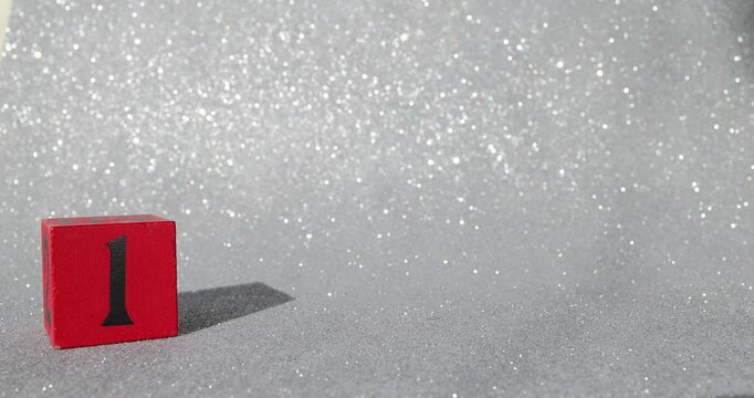 Footage of a red block with a silver glittery background showing the number 1 on a block being put down and taken back up again