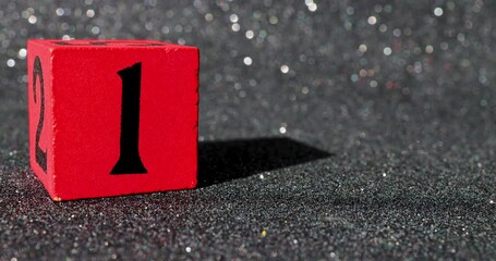 Footage of a red block with a black glittery background showing the number 1 on a block being put down and taken back up again