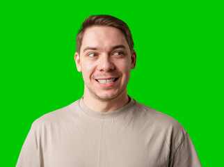 Smiling man in a beige shirt poses against a bright green background