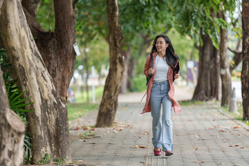 Happy confident young asian female university student walking on campus sidewalk with backpack and...
