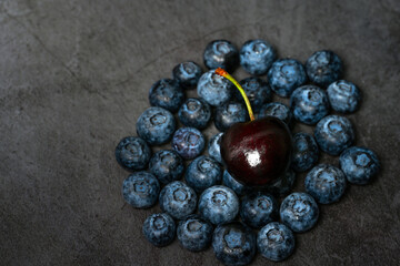 Closeup of blueberries and cherries on dark background.