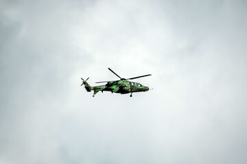 Helicopter is flying on isolated blue sky in mid-air background.