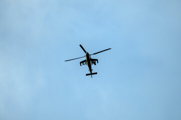 Helicopter is flying on isolated blue sky in mid-air background.