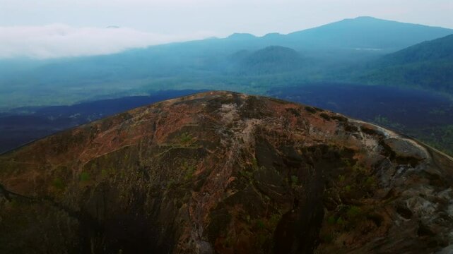 Aerial backwards shot of Paricutin Volcano with crater during cloudy day. Green valley landscape of Mexico. Wide shot.