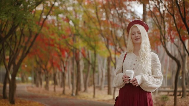 Lithuanian woman enjoying a drink while walking in Yangjae Forest Park, vibrant autumn colors around, space for text