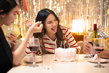 A birthday celebration with friends. A cake with candles is being served. Festive atmosphere with decorations, snacks, and happy people enjoying the party. Friends eating cake at birthday party.