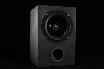 Black speaker on a black background with a bass reflex
