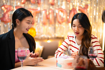 Group of Happy young Asian people friends enjoy and fun celebration birthday party at home dinner party. Beautiful woman excited with birthday cake and blowing candle.