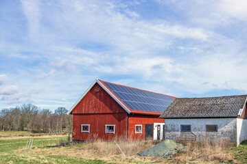 Obraz premium Solar panels on the roof at a red barn in a rural landscape