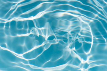 Blue water with ripples on the surface. Defocus blurred transparent blue colored clear calm water surface texture with splashes and bubbles. Water waves with shining pattern texture background.