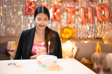 Asian people friends having celebration birthday party together at home with food and drink. Woman excited with birthday cake make a wish and blowing birthday candle with happiness.