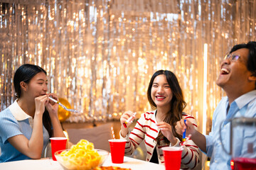 Three people celebrating with party blowers enjoying a festive atmosphere. Friends having fun at a party, expressing joy and excitement. Friends celebrating new year's eve party.