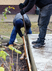 Two men are working on a project, one of them is using a saw